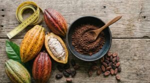 Cacau e emagrecimento: pó de cacau puro em tigela com fita métrica e folhas tropicais